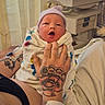 newborn, baby, hospital, tattoo, hand, hospital_wristband, blanket, hat, medical_equipment, patient, infant, bed, curtain, person, skin, face, crying, resting, care, healthcare