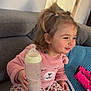 baby_bottle, casual_clothing, child, childhood, couch, cozy, cute, happy, home, indoor, leopard_print_pants, person, pigtails, pillow, pink_sweater, plate, smiling, snack, toddler, toy