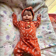 Allison joined the competition — help win amazing prizes! baby, infant, child, blanket, orange_clothing, headband, patterned_fabric, soft_texture, indoor, lying_down, cute, adorable, portrait, newborn, cozy, warm, sleepwear, colorful, face, hands