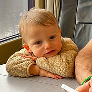 Raphaël a rejoint le concours — aidez-le/la à gagner de superbes lots ! arm, beige, child, curious, expression, face, furniture, hair, hand, indoor, jacket, light, person, portrait, sitting, skin, smartphone, table, toddler, window