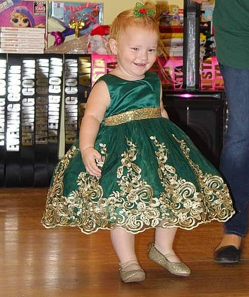 Paislyn is registered to the contest to win money with this photo: baby_toddler_clothing, child, costume, day_dress, dress, event, fashion_design, flooring, foot, formal_wear, fun, happy, hardwood, human_leg, joy, pattern, person, sandal, shelf, shoe