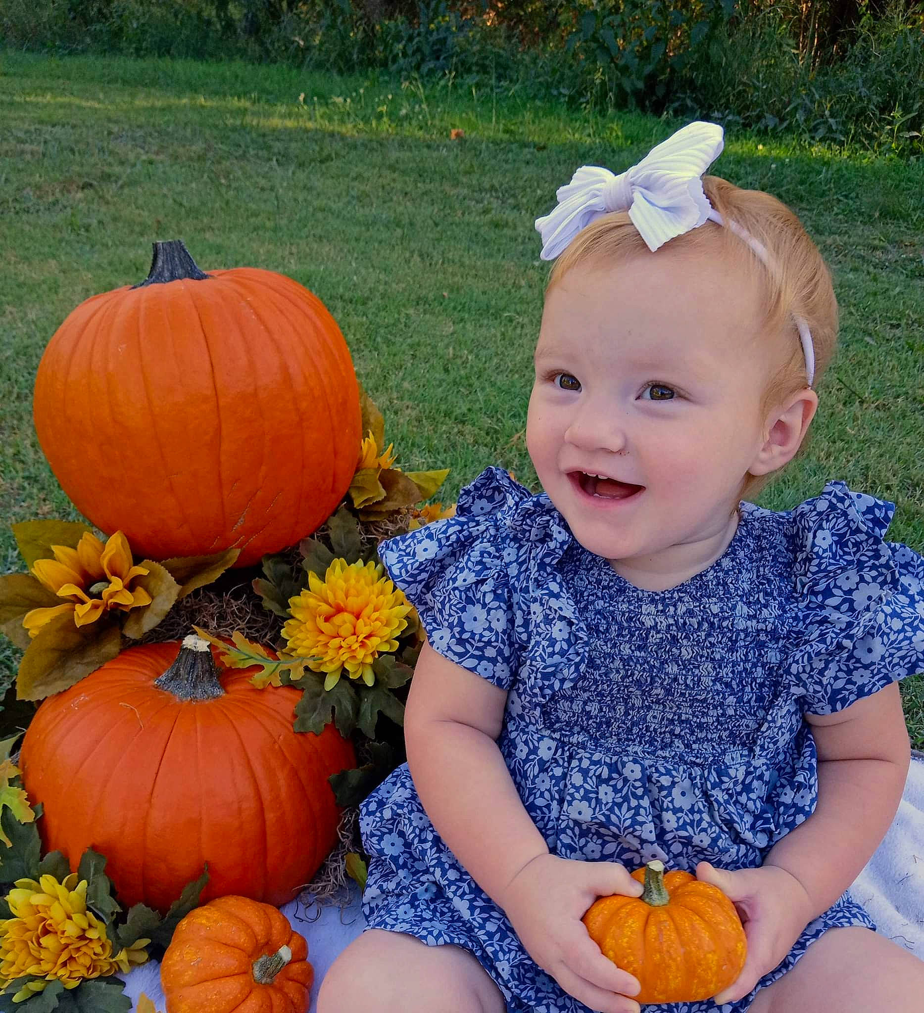 Paislyn is registered to the contest to win money with this photo: baby_toddler_clothing, calabaza, cucurbita, eye, facial_expression, gourd, grass, happy, joy, leaf, natural_foods, orange, organ, people, person, photograph, plant, pumpkin, smile, squash