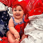 Elliott is registered to the contest to win money with this photo: baby, child, smiling, red_bow, headband, bandana, patterned_fabric, colorful, blue, white, red, sitting, happy, cute, infant, portrait, hand, foot, clothing, indoors
