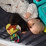 baby, child, black_cat, bed, crib, toys, book, onesie, animal_print, cuddling, floor, socks, blue_stripes, wooden_floor, infant, cute, sleepwear, pet, peaceful, indoor