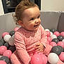 Mila a rejoint le concours — aidez-le/la à gagner de superbes lots ! toddler, child, baby, pink_pajamas, ball_pit, pink_balls, white_balls, gray_balls, curly_hair, smiling, indoor, playtime, happy, cute, young_child, seated, closeup, person, fun, toy