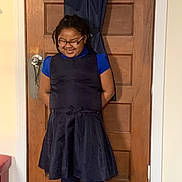 Alixandria joined the competition — help win amazing prizes! child, smiling, glasses, dress, blue_shirt, leggings, boots, indoor, door, wooden_door, happy, standing, hands_behind_back, curly_hair, home, floor, wall, casual_clothing, person, young