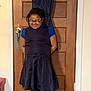 child, smiling, glasses, dress, blue_shirt, leggings, boots, indoor, door, wooden_door, happy, standing, hands_behind_back, curly_hair, home, floor, wall, casual_clothing, person, young