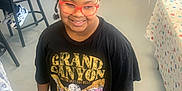 Alixandria joined the competition — help win amazing prizes! child, girl, afro_hair, glasses, black_tshirt, graphic_tshirt, boots, indoor, floor, table, tablecloth, bracelet, smile, person, fashion, hairband, red_glasses, standing, casual, happy