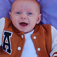 Abel is registered to the contest to win money with this photo: apparel, baby, blue_eyes, buttoned_jacket, casual_wear, child, clothing, cute, face, happy, head, infant, jacket, letter_a, lying_down, person, portrait, purple_blanket, smile, young_child