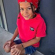 Maysson a rejoint le concours — aidez-le/la à gagner de superbes lots ! black_shoes, braided_hair, casual_clothing, child, concrete, crouching, cute, daylight, denim_shorts, fashion, happy, outdoor, person, portrait, red_bandana, red_shirt, smiling, sneakers, wall, young