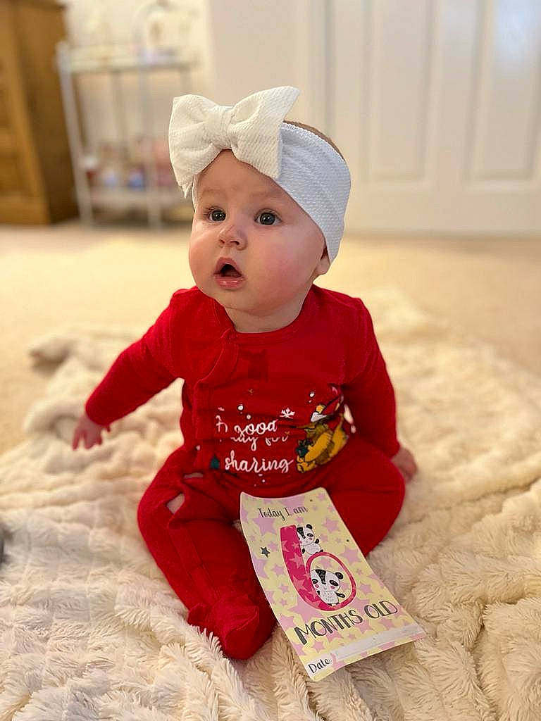 Elouise is registered to the contest to win money with this photo: baby, baby_toddler_clothing, child, comfort, flooring, fun, happy, headwear, magenta, pattern, peach, person, portrait_photography, sitting, skin, sleeve, surprise, toddler, wood