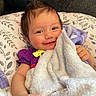 Alayna joined the competition — help win amazing prizes! baby, child, infant, smiling, portrait, closeup, indoor, blanket, pillow, bedding, purple_clothing, yellow_bow, brown_hair, blue_eyes, sitting, lying_down, cozy, couch, soft_texture, happy