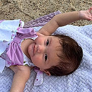 Alayna is registered to the contest to win money with this photo: baby, infant, child, portrait, lying_down, smiling, happy, outdoor, blanket, lavender, pastel_clothing, dress, brown_hair, face, eyes, arm, hand, sand, cozy, photography