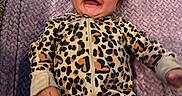 Alayna is registered to the contest to win money with this photo: baby, infant, child, smiling, happy, portrait, face, eyes, hair, leopard_print, onesie, jumpsuit, blanket, lavender, textile, lying_down, indoor, close_up, joyful, photography