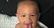 Alexander joined the competition — help win amazing prizes! baby, child, infant, portrait, face, smiling, tongue_out, sitting, indoors, bedroom, bedding, cushion, pillow, patterned_fabric, bare_shoulders, short_hair, brown_eyes, playful, closeup, portrait_photography
