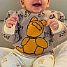 baby, child, smiling, sitting, yellow_cap, teddy_bear_sweater, cute, happy, indoors, feet, barefoot, clothing, portrait, infant, playful, person, casual, cozy, cute_expression, headwear