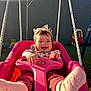 baby, child, swing, pink, smiling, headband, outdoor, playground, toy_car, grass, sunlight, happy, person, feet, clothing, rope, seat, infant, cute, playtime