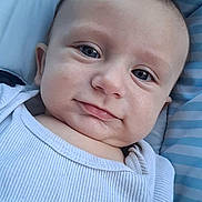 Gabriel participe au concours pour gagner de l'argent avec cette photo : baby, blue_stripes, cheeks, child, close_up, cushion, cute, eyes, face, head, indoors, infant, mouth, person, portrait, skin, smile, soft_light, white_clothing, young_child