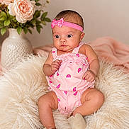 Aria joined the competition — help win amazing prizes! baby, infant, pink, romper, headband, flower_vase, flowers, blanket, soft_texture, cute, child, portrait, indoor, sitting, footwear, decor, adorable, skin, person, young_child