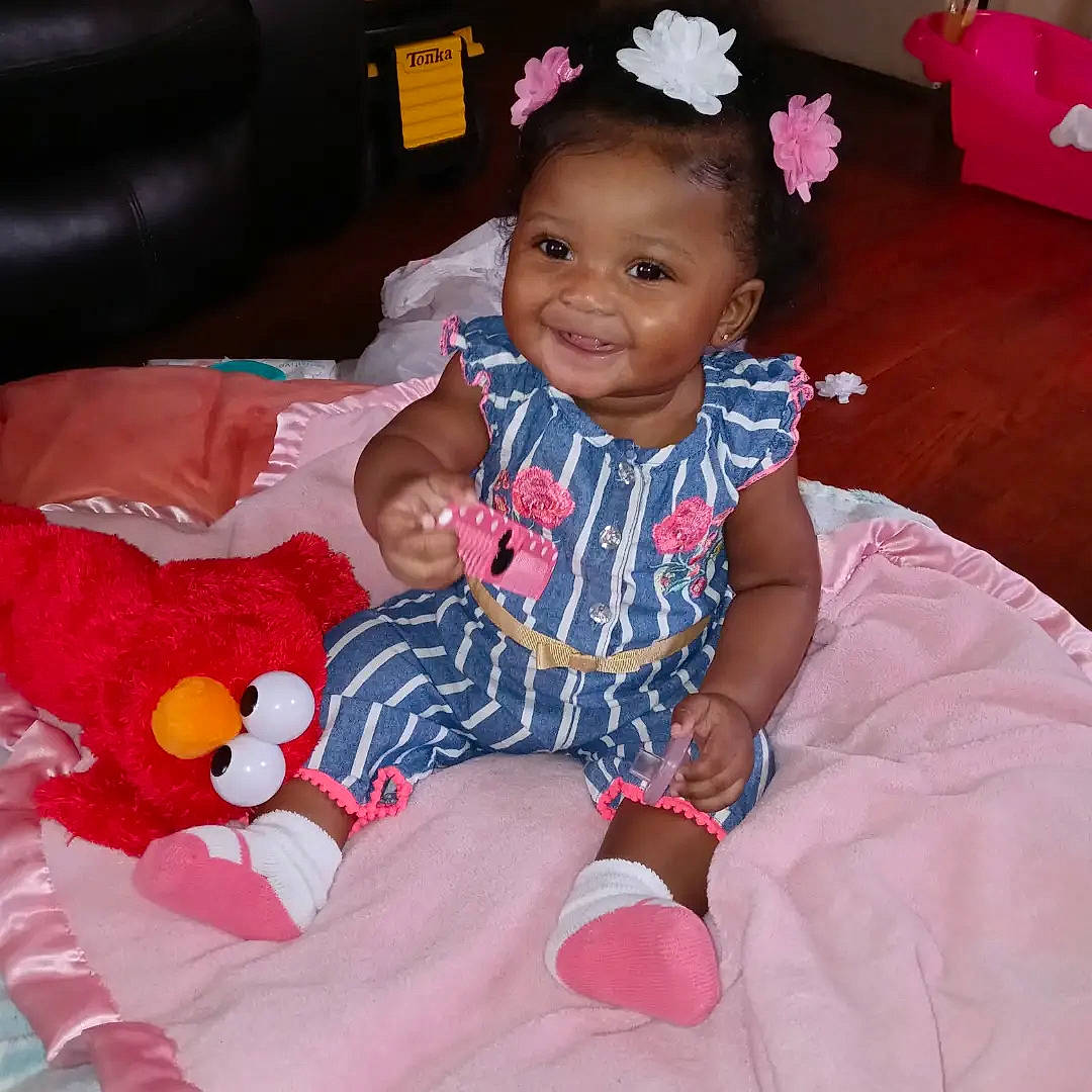 Dior is registered to the contest to win money with this photo: baby, baby_toddler_clothing, child, comfort, eye, face, finger, flower, fun, happy, head, human_body, joy, lap, organ, person, pink, skin, smile, textile