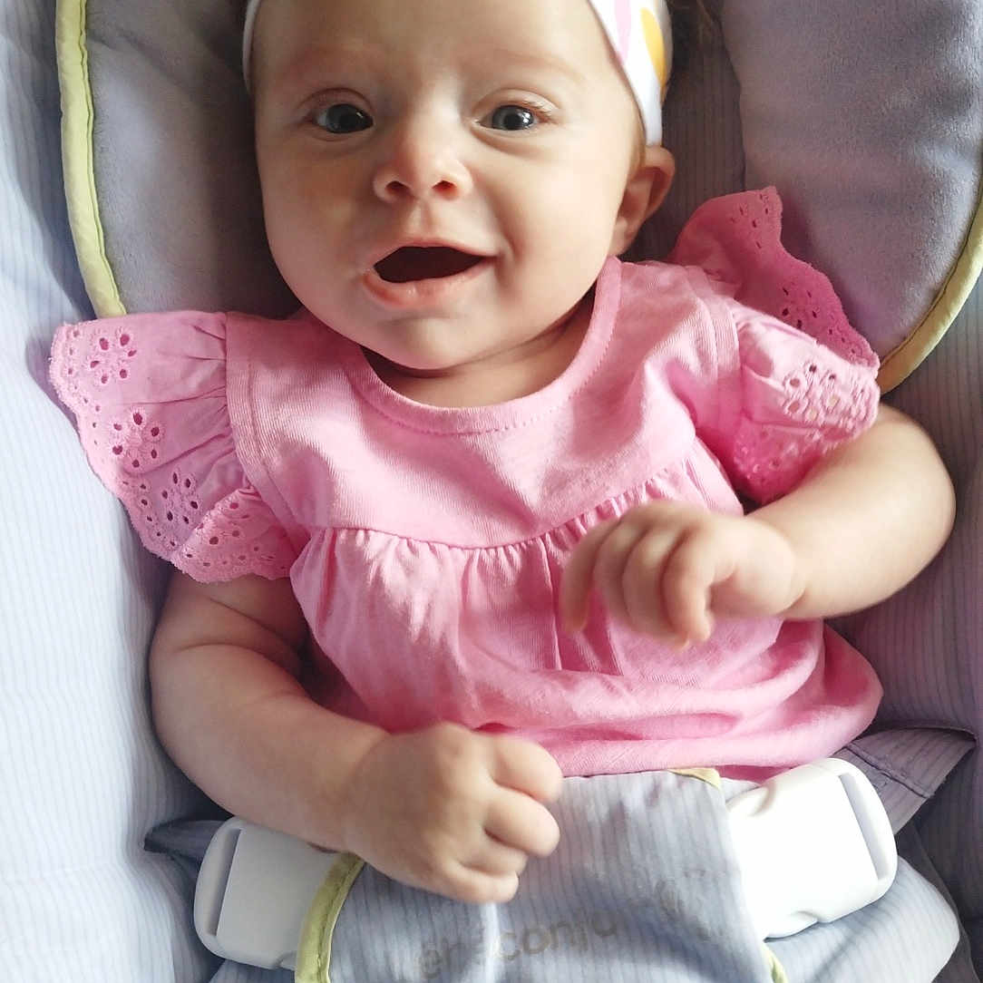 Athéna participe au concours pour gagner de l'argent avec cette photo : apparel, baby, baby_seat, bow, child, comfort, cushion, cute, face, hands, happy, headband, indoors, infant, pink_dress, playful, portrait, seatbelt, smiling, young_child