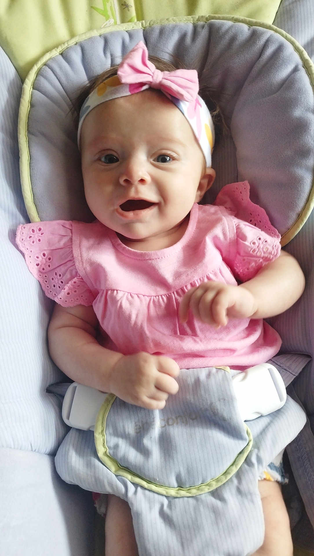 Athéna participe au concours pour gagner de l'argent avec cette photo : baby, infant, child, pink_dress, headband, bow, smiling, happy, cushion, baby_seat, comfort, indoors, cute, portrait, young_child, hands, face, apparel, seatbelt, playful