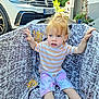 blue_eyes, car, casual, child, curious, curly_hair, greenery, grip, hand, outdoor, patterned_fabric, playpen, shorts, sitting, striped_shirt, suburban, sunlight, toddler, vehicle, young_child