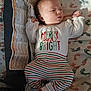 baby, infant, pajamas, clothing, footprint_pattern, blanket, sleepwear, child, cute, newborn, portrait, person, lying_down, indoors, soft_lighting, striped_pants, white_socks, holiday_theme, sleepy, cozy