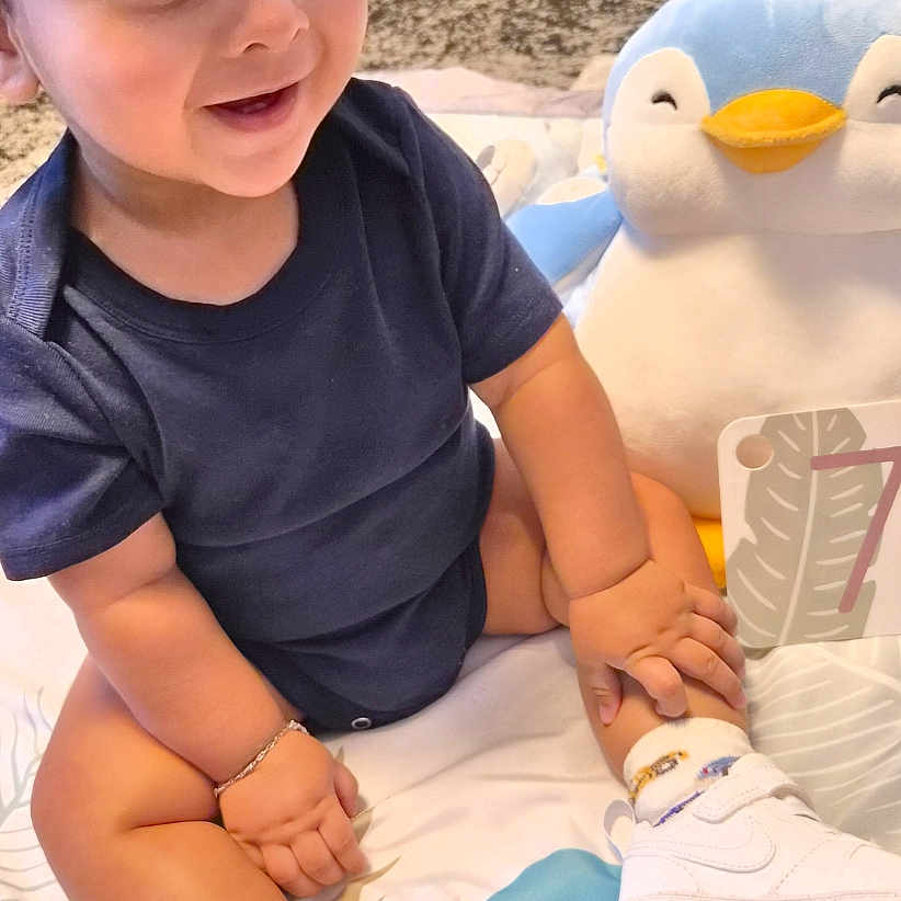 Zaaviar participe au concours pour gagner de l'argent avec cette photo : baby, blanket, bracelet, cap, card, child, cute, footwear, happy, indoor, number, penguin, person, playing, plush_toy, sitting, smiling, sneakers, sock, toddler