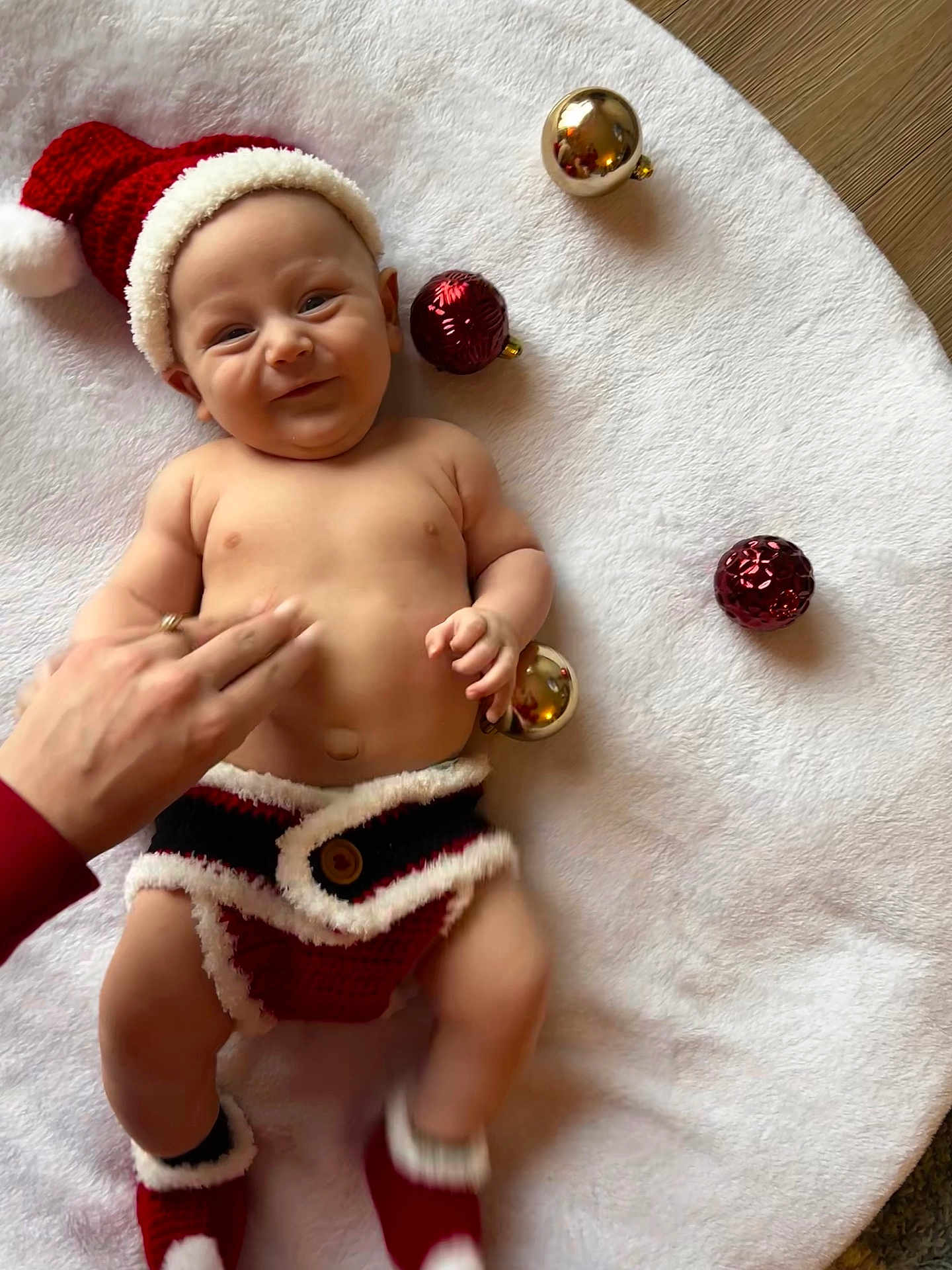 Giovani joined the competition — help win amazing prizes! baby, infant, santa_hat, christmas, holiday, ornaments, blanket, hand, smile, cute, festive, knitwear, red, white, floor, decoration, cheerful, lying_down, holiday_season, celebration