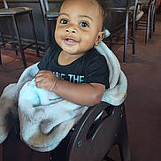 Shon joined the competition — help win amazing prizes! baby, child, smiling, portrait, high_chair, restaurant, indoor, blanket, black_shirt, seated, curly_hair, face, eyes, happy, infant, furniture, chairs, dining_area, photography, daylight