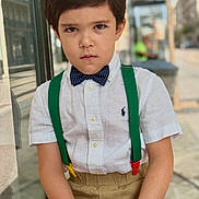 Niko participe au concours pour gagner de l'argent avec cette photo : bow_tie, boy, brown_hair, casual, child, expression, face, fashion, outdoor, pants, person, portrait, serious, shirt, short_sleeve, sitting, street, suspenders, window_reflection, young