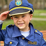 Dimitri a rejoint le concours — aidez-le/la à gagner de superbes lots ! badge, blue_clothing, blurred_background, button, casual, child, costume, eyes, face, grass, hand, happy, hat, jacket, outdoor, person, police_uniform, portrait, smile, young
