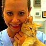 woman, cat, orange_tabby, smiling, scrubs, indoor, veterinary, pet, animal, holding, face, portrait, watch, name_tag, healthcare, person, cute, happy, close_up, friendly