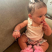Ezmerai joined the competition — help win amazing prizes! baby, child, girl, sitting, couch, pink_socks, fluffy_socks, hair_bows, bracelet, white_top, floral_shorts, cute, indoor, nose_picking, adorable, infant, portrait, skin, hand, face