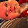 Alina joined the competition — help win amazing prizes! baby, closeup, face, red_clothing, button, striped_surface, infant, skin, eyes, mouth, head, young_child, portrait, lying_down, curious, cute, human, expression, indoors, person