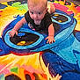 baby, child, crawling, carpet, colorful, cartoon, indoor, dog, animal, floor, person, diaper, shirt, pet, living_room, furniture, cute, playful, young_child, carpet_design