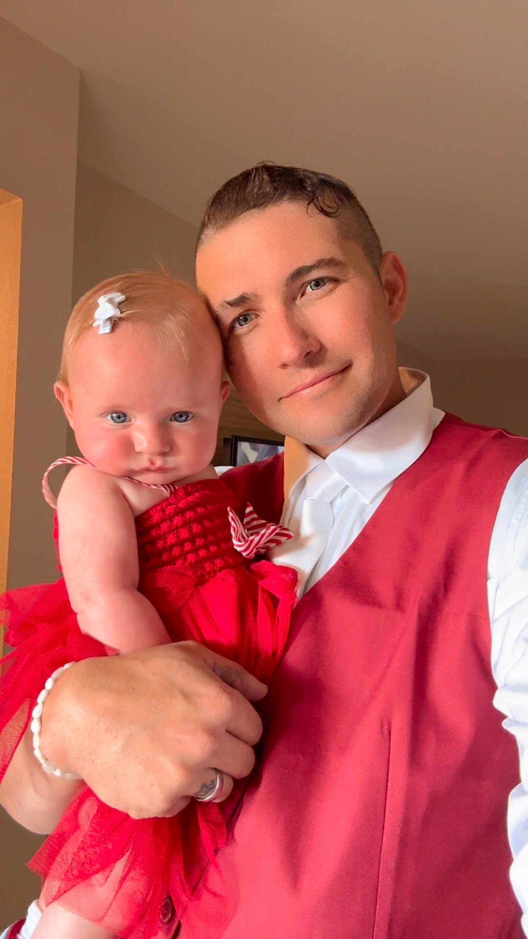 Alina joined the competition — help win amazing prizes! baby, adult, red_dress, red_vest, portrait, indoors, holding, serious_expression, blue_eyes, short_hair, bracelet, bow, person, family, close_up, skin, head, hand, clothing, smile