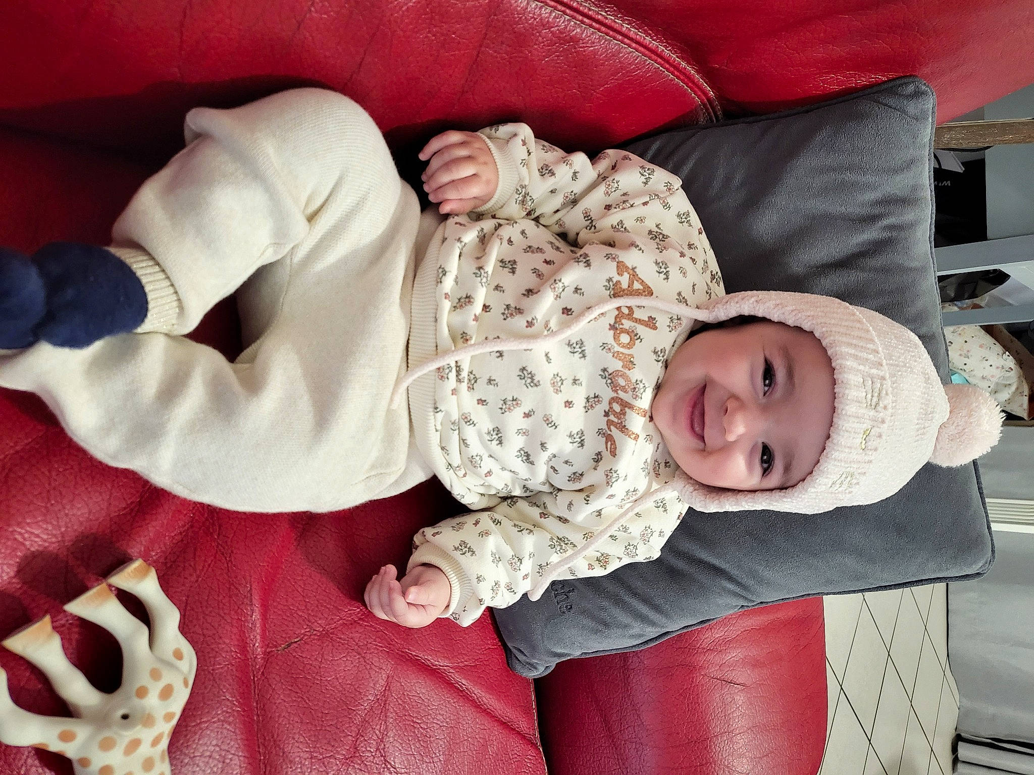 Faustine participe au concours pour gagner de l'argent avec cette photo : baby, baby_products, baby_sleeping, baby_toddler_clothing, child, comfort, eye, happy, head, headwear, human_body, joy, lap, mouth, person, red, sitting, skin, sleeve, smile