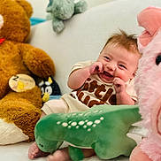 Micah joined the competition — help win amazing prizes! baby, infant, smiling, stuffed_animal, teddy_bear, pig, dinosaur, plush_toy, couch, indoor, cute, child, happy, soft_toy, furniture, cozy, playful, two_months, person, portrait