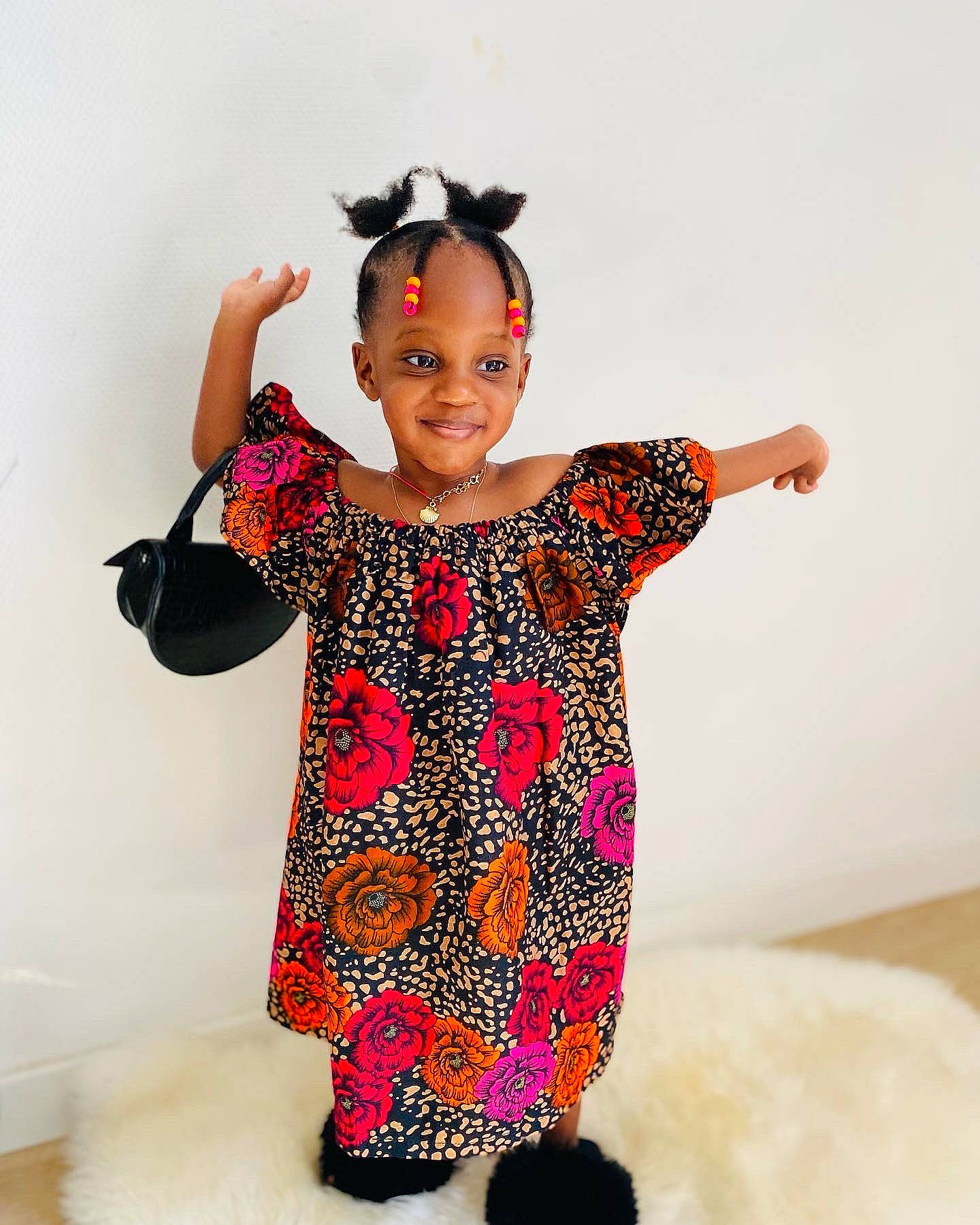 Maya participe au concours pour gagner de l'argent avec cette photo : arm, baby_toddler_clothing, day_dress, dress, face, fashion_design, finger, gesture, happy, human_body, joy, magenta, neck, one_piece_garment, pattern, person, pink, shoulder, sleeve, smile