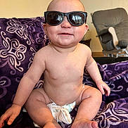Bryson is registered to the contest to win money with this photo: accessories, baby, bodypart, clothing, cushion, diaper, face, finger, glasses, hand, happy, head, homedecor, person, photography, portrait, shorts, sitting, sleeve, sunglasses