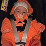 baby, blanket, booties, car_seat, child, clothing, comfort, cute, face, hat, indoor, infant, mittens, orange_outfit, pacifier, plant, pumpkin_costume, safety_harness, seat, window