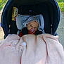 baby, baby_accessory, blanket, car_seat, child, cozy, cute, face, grass, hat, infant, outdoor, pacifier, pink, plush, relaxed, seatbelt, shade, sidewalk, sunlight
