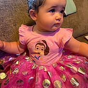 Dani is registered to the contest to win money with this photo: baby, child, toddler, portrait, sitting, couch, indoor, curly_hair, pink_dress, tutu, polka_dots, sparkles, cartoon_character, princess, colorful, cute, looking_away, outstretched_arms, face, clothing