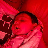 Braelynn is registered to the contest to win money with this photo: baby, sleeping, blanket, red_light, pacifier_clip, infant, face, soft_texture, close_up, indoors, peaceful, child, warm_color, rest, young, portrait, cute, comfort, head, skin