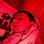 baby, sleeping, blanket, red_light, pacifier_clip, infant, face, soft_texture, close_up, indoors, peaceful, child, warm_color, rest, young, portrait, cute, comfort, head, skin