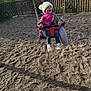 Elina a rejoint le concours — aidez-le/la à gagner de superbes lots ! toddler, child, swing, playground, gravel, hat, jacket, pink_clothing, white_hat, outdoor, daylight, fence, trees, happy, smiling, person, play, fun, nature, casual_clothing