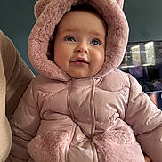 Ruby joined the competition — help win amazing prizes! baby, child, pink_coat, hood, fur, blue_eyes, face, person, portrait, indoor, warm_clothing, hand, sleeve, cuddly, cute, looking_up, smiling, fuzzy, winter, holding