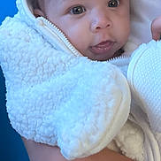 Davina joined the competition — help win amazing prizes! baby, infant, child, person, face, eyes, clothing, jacket, hand, holding, indoor, wall, blue, white, fur, texture, curly_hair, portrait, cute, warm